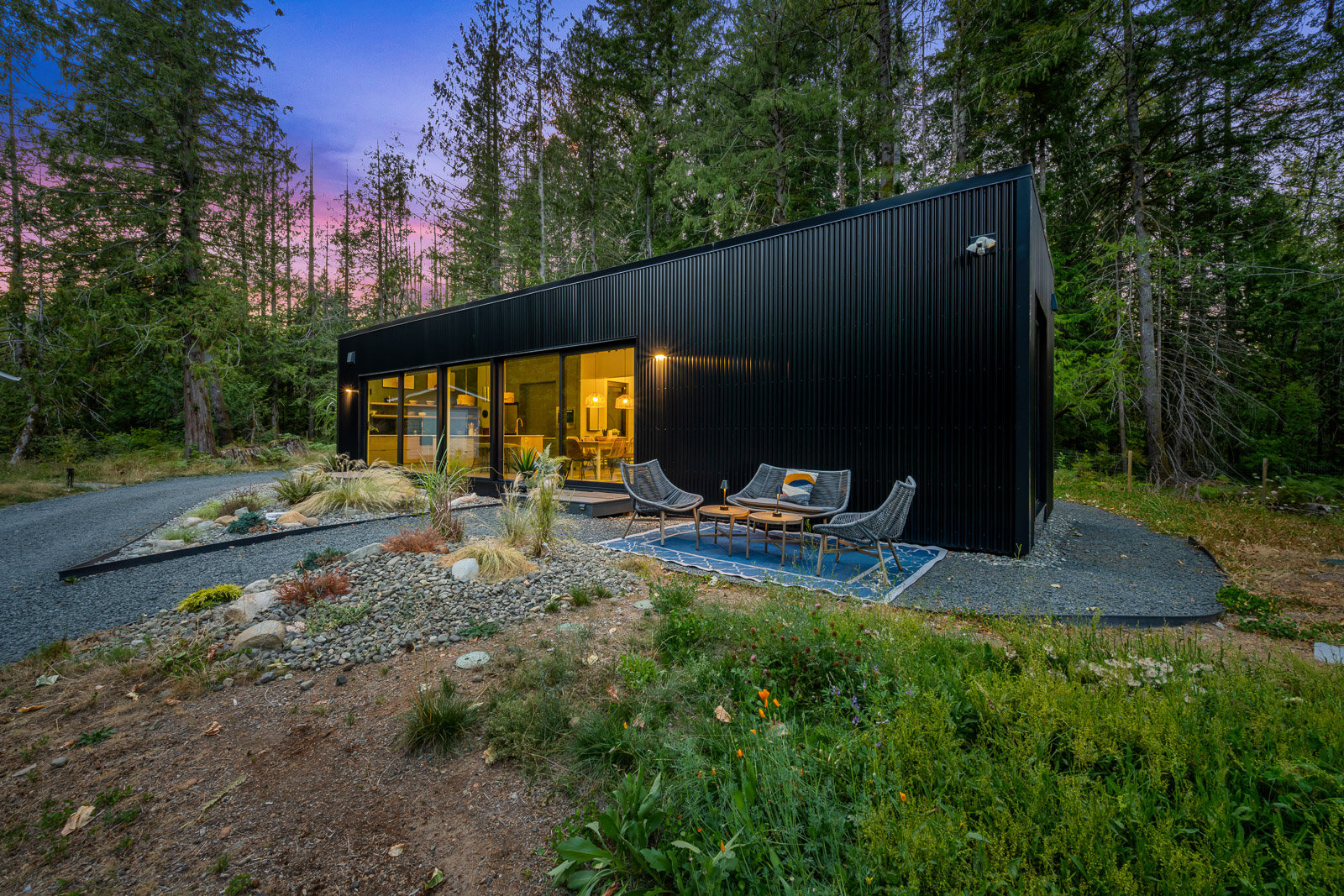 The main residence glowing at twilight, forest silhouettes against a pink sky