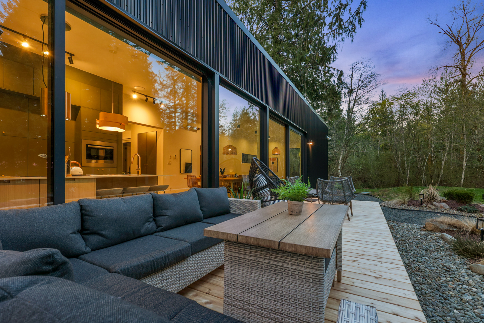 The main residence at twilight — both wings glowing, connected by the glass gallery, forest all around
